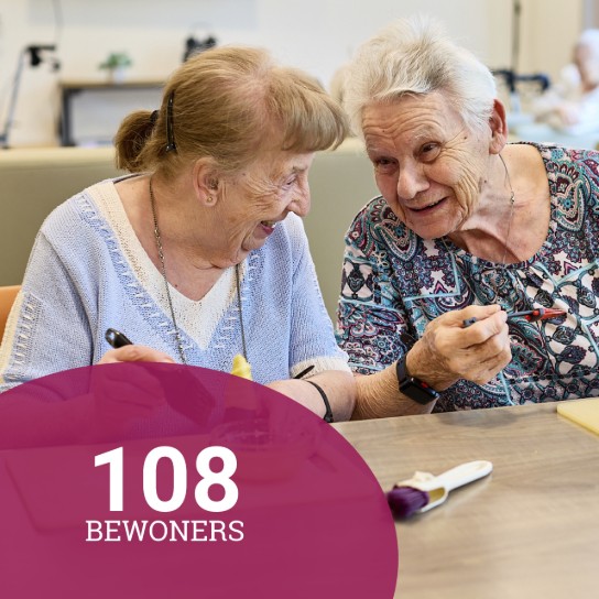 Twee oudere vrouwen lachen en praten samen terwijl ze aan een tafel zitten. (vergroot foto)